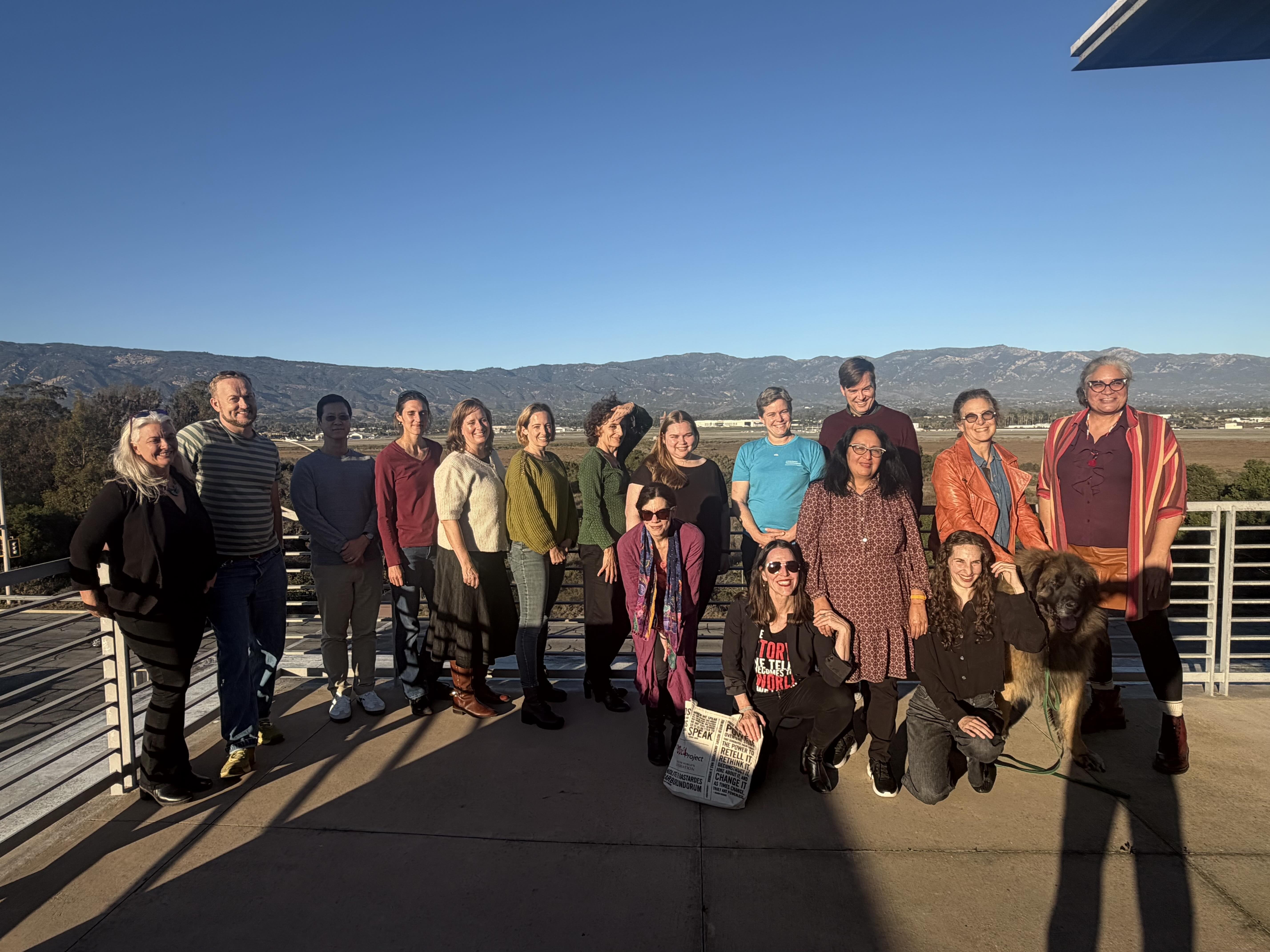 The UCSB PVF 2025 Cohort poses for a group photo outdoors on a sunny day. The group of about 15 people and a dog stand on a patio, with a distant mountain range and clear blue sky in the background.